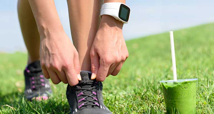runner tying shoe with fitness watch on