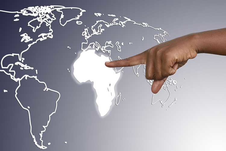 photo of hand pointing to African continent on virtual world map